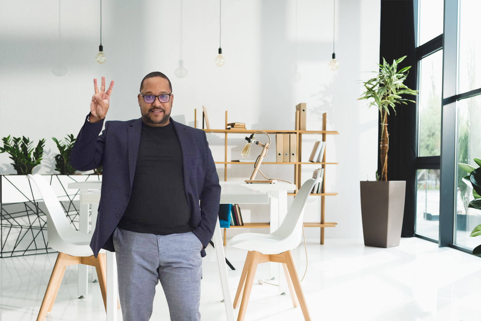 A man stands in a modern office, holding up three fingers with his right hand. Dressed smartly, he exemplifies the confidence and style often seen among digital marketing experts today.